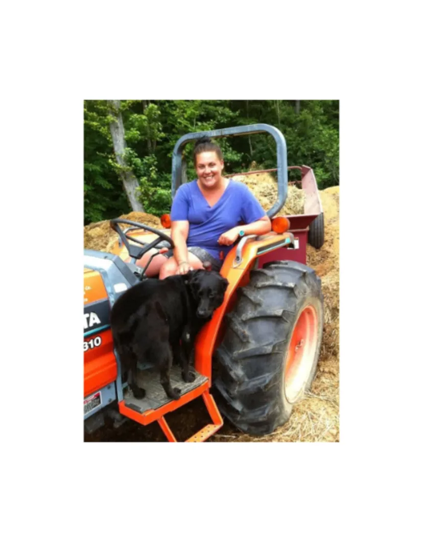 A photo of Lindsay on a tractor with their dog